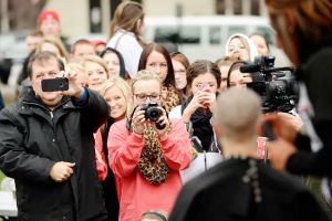 Group of people using cameras to capture indidvidual shaving their head