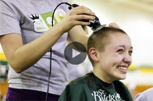 Young woman smiling while her head is being shaved