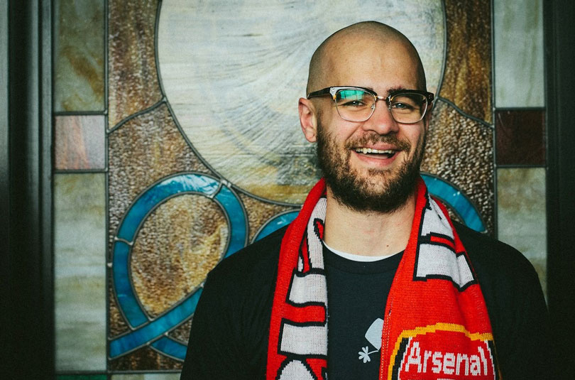 Andrew smiles wearing an Arsenal scarf